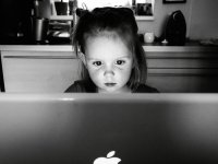Young girl sitting at a table looking intently at something on a laptop