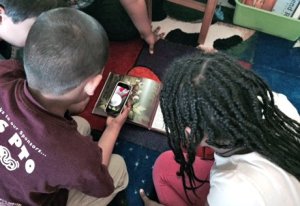 Boy comparing a flower picture on a mobile device to one in a book