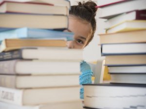 Student behind a pile of books