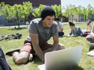 Student coding outdoors on a laptop