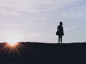 Silhouette of a person at the top of a hill watching the sun rise