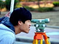 A photo of a high school male student using survey equipment.