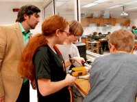 Teacher and students gathered around looking down at a project