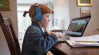 Elementary-aged girl watches National Geographic Explorer Classroom on her laptop at home