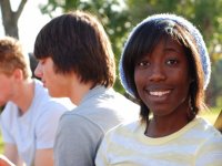 Girl sitting with two boys smiling at the camera