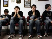 The same teenage boy is seen sitting in four different chairs, next to each other, waiting in a school building.