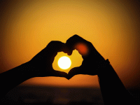 Hands forming a heart with the sun in the middle