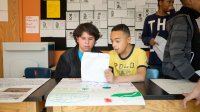 Two middle school students work on writing together in classroom