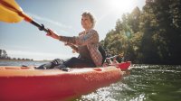 A woman kayaks on a lake on her own.