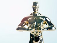 A closeup of an Oscar award, a small, golden statue of a standing naked man. His hands are in front of him, below his chest, holding a wreath.