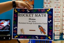 Teacher holding up Dorian's Rocket Math certificate that says he rocketed through subtraction facts
