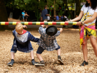 A photo of 2 elementary-school boys going under a limbo bar.