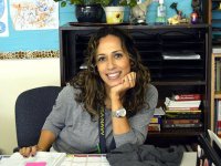 Smiling woman sitting at her teacher's desk