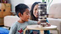 Young boy playing the game Jenga with his mother at home