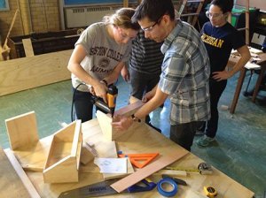 A photo of a teacher helping a student use the drill.