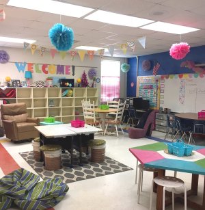 A classroom with different shaped tables and non-traditional seating, like bucket chairs and shoe-shaped chairs