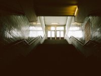 Looking up a flight of stairs in school toward double doors and the outside