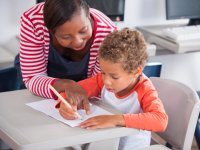 Teacher helping a little boy with his work