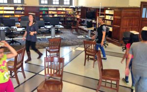 Students playing musical chairs while balancing a book on their head