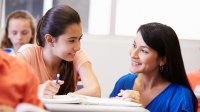 A high school student shares a smile with her teacher. 