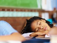 Girl sound asleep at her desk, arms crossed across her books