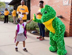 Kindergarten student high-fives Freddy the Frog.