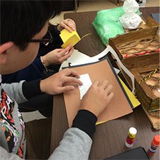 A photo of a student glueing pieces of colored paper together.