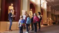 Young students learn while looking at an ancient statue in a museum.