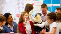 photo of students and teachers playing with a puppet