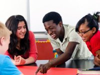 Four kids around a desk as one points to something