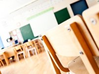 Wide shot of a tidy, well-lit classroom with lots of open space with focus on the back of a chair