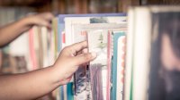 Photo of a bookshelf with students’ hands reaching in to make selections