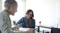 An instructional coach and a teacher discuss some paperwork.