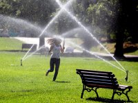 photo of a woman running through the sprinklers