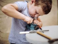 Young boy determined to make something fit using a vice