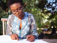 Young woman sitting outside writing in a binder