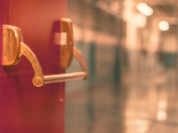 Photo of a door opening to an empty school hallway
