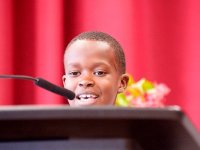 Young boy speaking, almost hidden by the podium he's standing behind