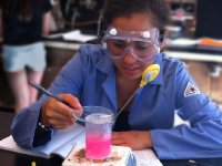Girl wearing safety goggles heating up a pink liquid on a Bunsen Burner