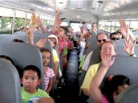 photo of students on a bus with their hands in the air