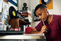 Teenager writing at his desk in his bedroom