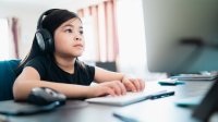 Young girl at home on computer doing distance learning. 