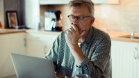 Man sitting in his kitchen working on his laptop