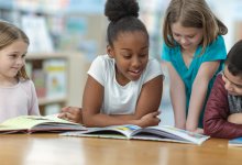 Small group of elementary students read books together