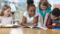 Small group of elementary students read books together