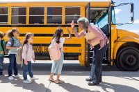 Elementary school principal high fives students as they board their school bus