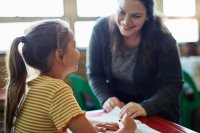 Teacher smiling and working with elementary school student