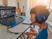 A young Asian boy participates in online learning