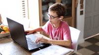 Elementary aged boy on laptop distance learning at home