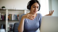 Teacher wearing headphones and talking during a video chat on her laptop